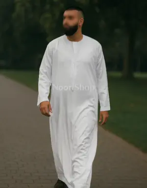 Mann trägt weißen Herren Qamis mit kurzem Kragen von Noor Shop und läuft auf einem Weg im Park