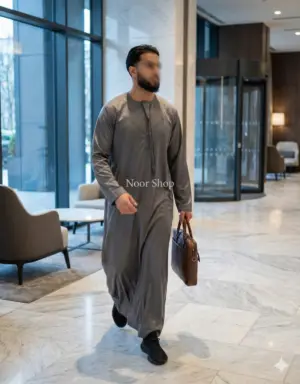 Muslimischer Mann trägt grauen Business-Thobe von Noor Shop in einer modernen Lobby