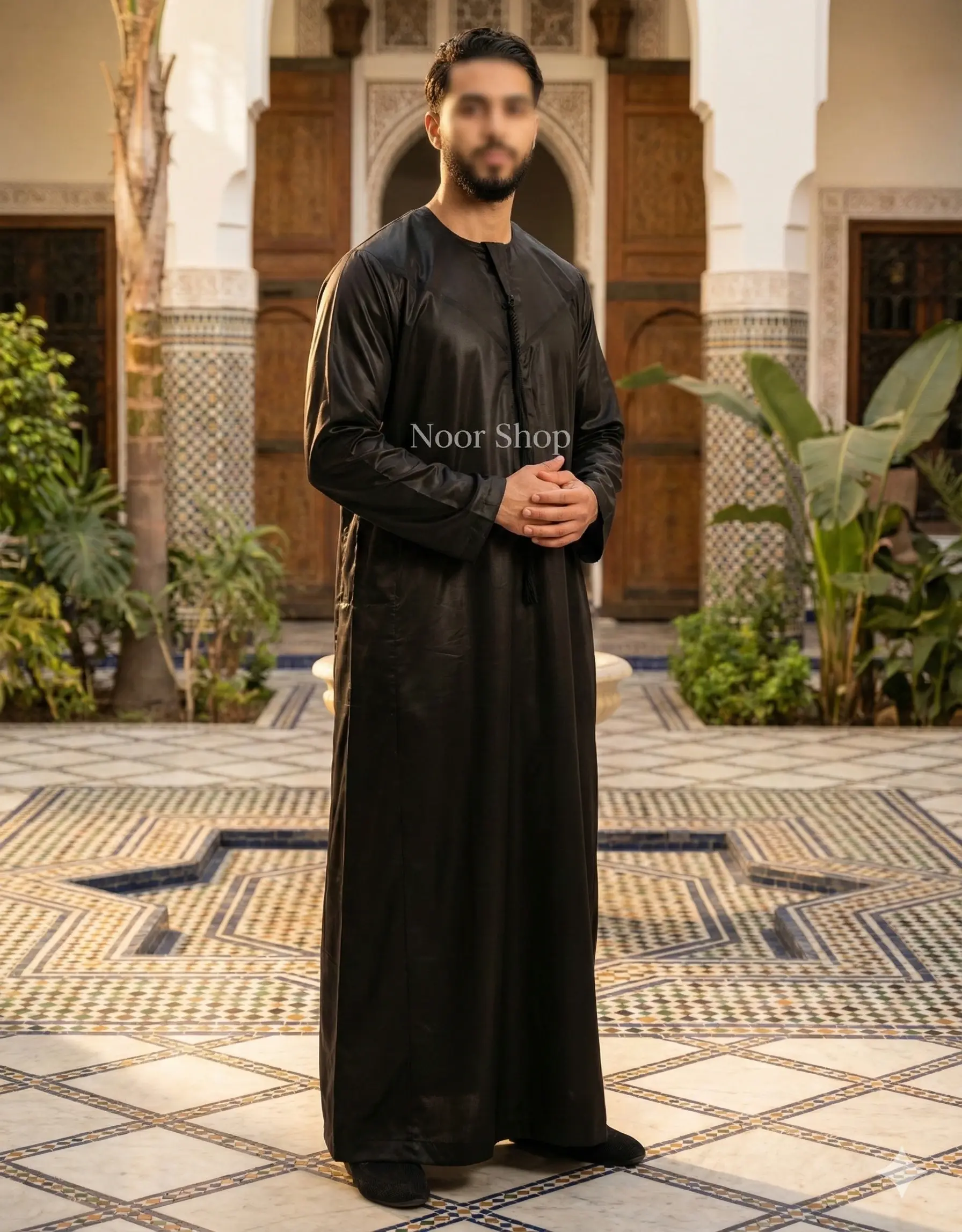 Muslimischer Mann trägt schwarzen glänzenden Thobe im marokkanischen Innenhof – Noor Shop