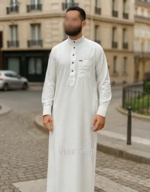 Mann trägt weißen Herren Thobe mit Stehkragen, Knopfleiste und Brusttasche von Noor Shop auf einer Kopfsteinpflaster Straße